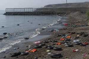 Vista del espigón del Tarajal, en Ceuta, con la playa vacía y flotadores abandonados tras una entrada masiva de personas, símbolo de una crisis fronteriza.